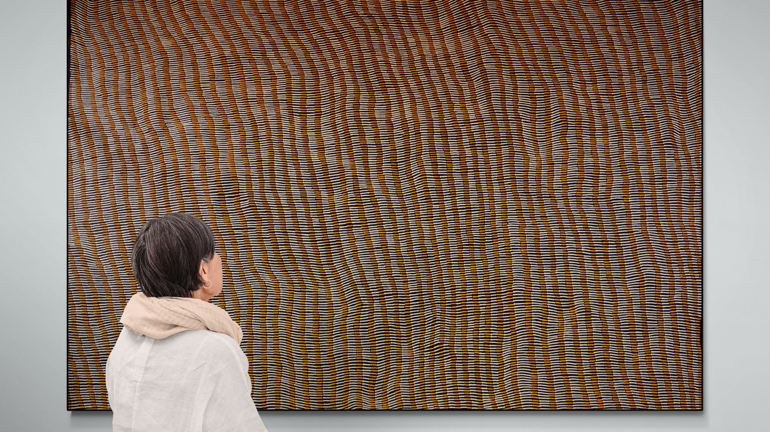 Woman looking at a large artwork by Yukultji Napangati