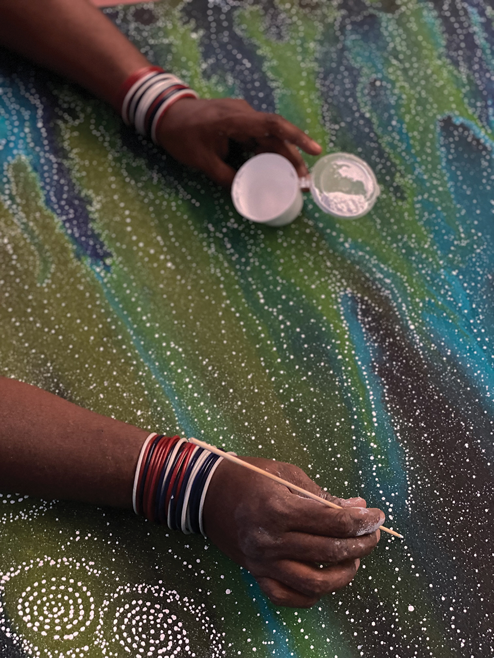 Close Up image of Athena Granites applying fine dots onto one of her 7 sisters artworks