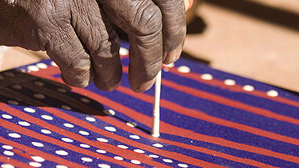 Extreme close up of artist Shorty Jangala Robertson applying dots to his painting