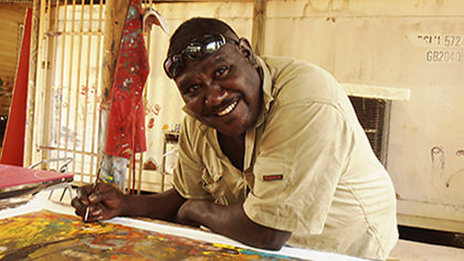Artist Silas Hobson smiling while painting at the art centre