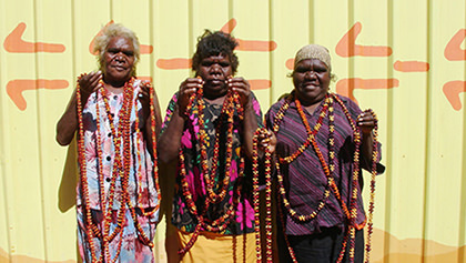 Three Aboriginal women displaying local bush seed necklaces