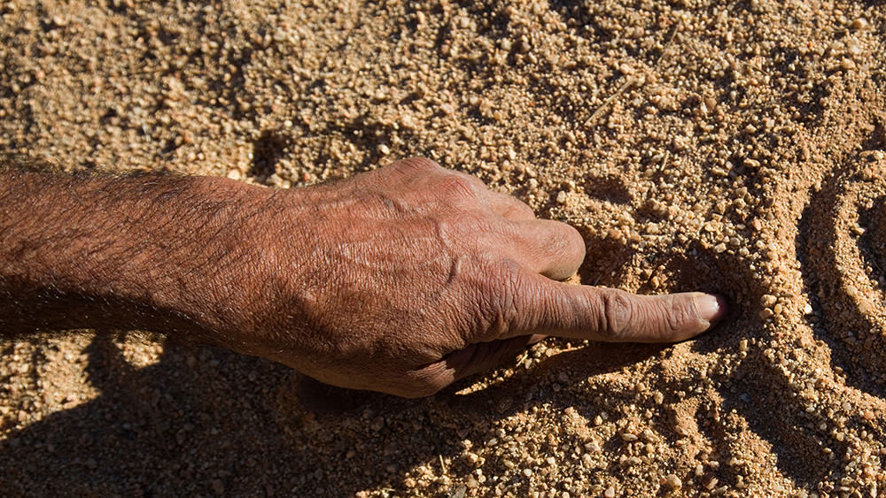 hand drawing symbols in the sand