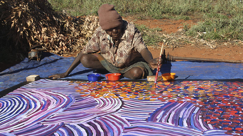 Gayla Pwerle painting outside in the Central desert